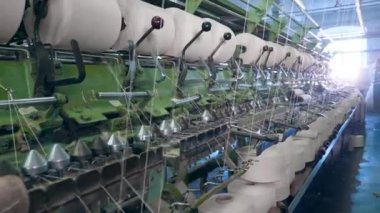 Beyaz iplikler sarma bobinler ile dikiş tezgahı. Modern tekstil fabrikası.