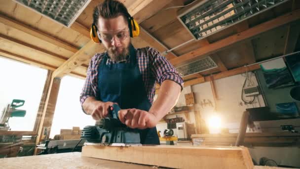 Een man werkt met hout, met behulp van een schrijnwerk tool. — Stockvideo