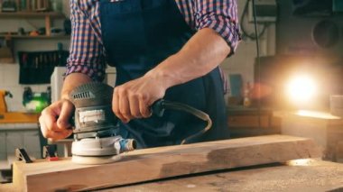 Adam ahşap bir parça üzerinde parlatma makinesi ile çalışır.