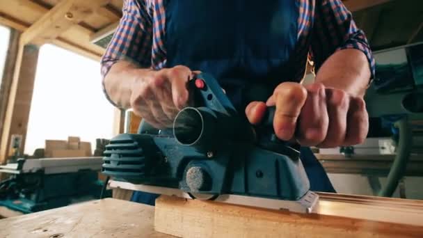 Un carpintero blanquea palo de madera con un instrumento . — Vídeo de stock