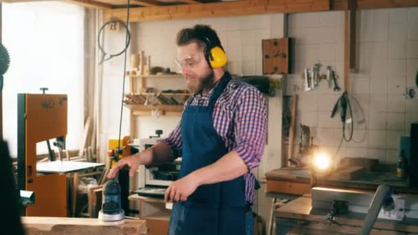 En snickare arbetar på en snickeri, leende på kameran. — Stockvideo