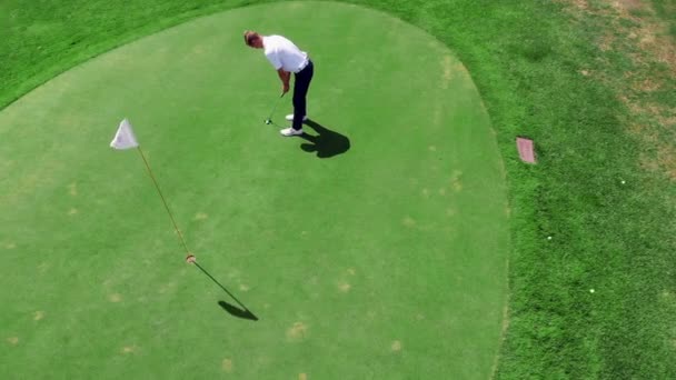 Golfista masculino coloca bola branca em um buraco em um campo . — Vídeo de Stock