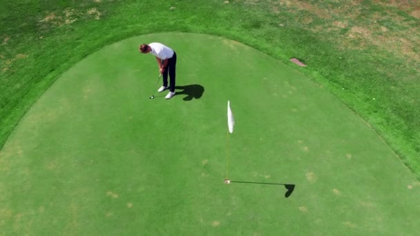 Гравець вдарив м'яч, щоб отримати його в отвір на гольф-курс. — стокове відео