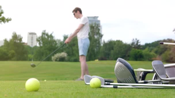 Golf sahası ve topa vurmayı hedefleyen bir adam. — Stok video