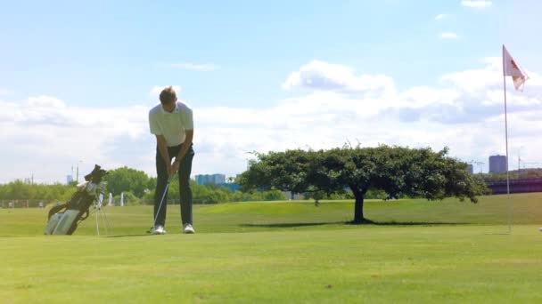 Молодой человек играет в гольф и забивает. — стоковое видео
