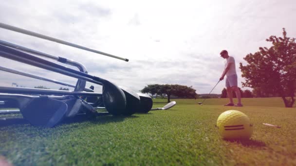 Green lawn with clubs and a male player taking a shot — Stock Video