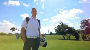 Erkek golfçü sahada duruyor ve gülümsüyor