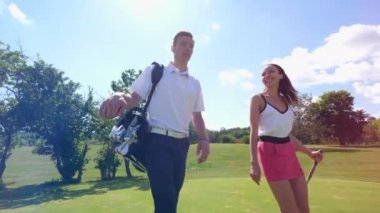 Golf sahası boyunca yürüyen bir erkek ve bir kadın ile