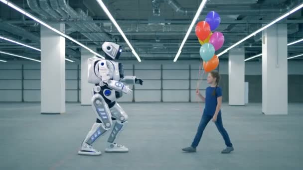 En tjej ger ballonger till en Droid, sidovy. — Stockvideo