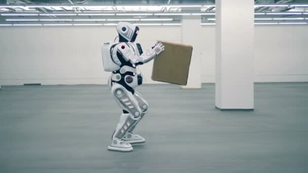 Robô branco carrega uma caixa, vista lateral . — Vídeo de Stock