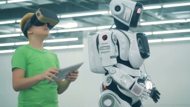Grundskolans utbildningskoncept. En pojke bär VR-glasögon medan en robot rör sig, närbild. — Stockvideo