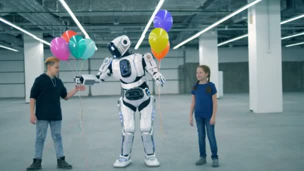 Robot çocuklara balon verir, yakından. Okul çocuğu, eğitim, fen sınıfı kavramı. — Stok video