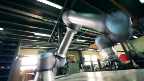Eén metalen arm beweegt tijdens het werken aan een fabrieks tafel. — Stockvideo