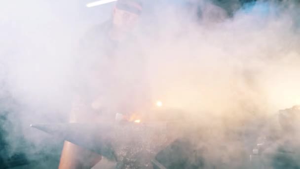 Manlig smed är att smida ett verktyg i moln av rök — Stockvideo