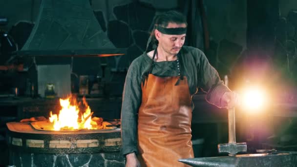 Un artesano sostiene un martillo contra herreros — Vídeo de stock