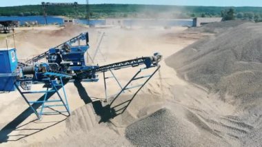 Bir taş ocağında çalışan konveyörden ezilmiş taş düşer. Madencilik sektörü kavramı.