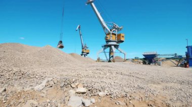 Bir vinç ezilmiş taşları kovaya koyarak, yığıyor..