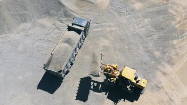 Sarı traktör, bir kamyonu kırıştırıyor.