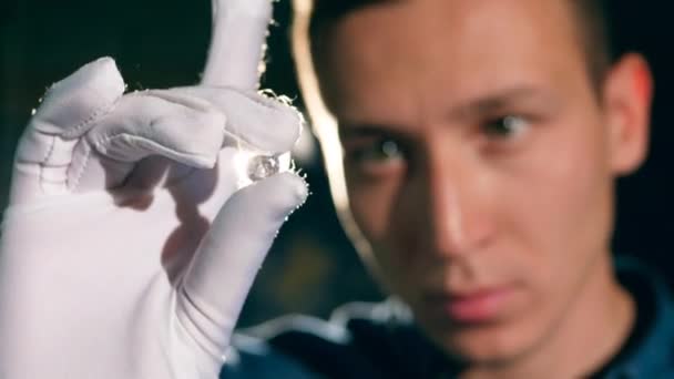 Hombre joyero está mirando la piedra preciosa contra la luz. Joyero hace una pieza de joyería — Vídeos de Stock