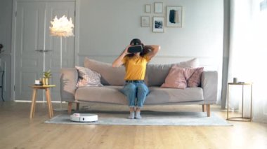 Bir Bayan robot Hoover ile odada VR-gözlük koyarak