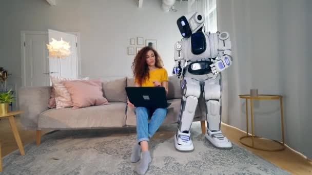 Mensachtige Cyborg kijkt naar een dame die aan een laptop werkt — Stockvideo