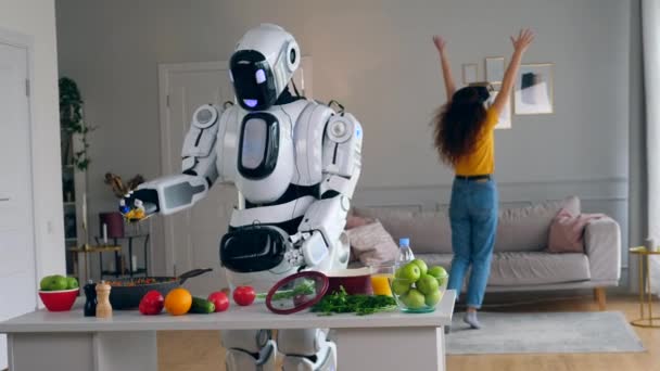 Robô semelhante ao humano está cozinhando com uma senhora de óculos VR se movendo perto dele — Vídeo de Stock