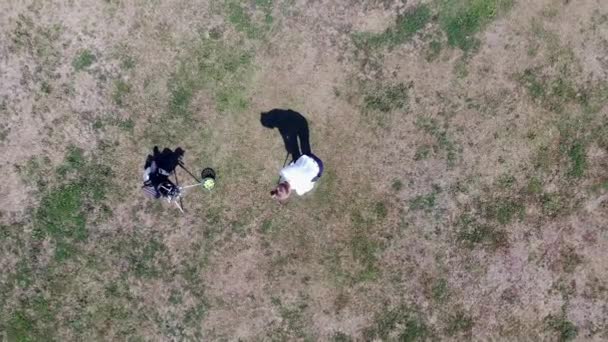 The man is striking a golf ball on the dusty lawn — Stock Video