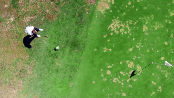 Manlig spelare är slående en golfboll med styrka i en topp-vy — Stockvideo