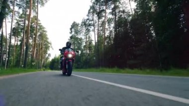 Motosikletçi orman yolu boyunca sürüş