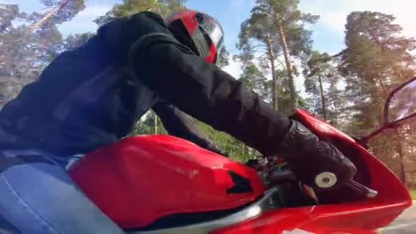 En person i en hjälm rider en röd motorcykel — Stockvideo