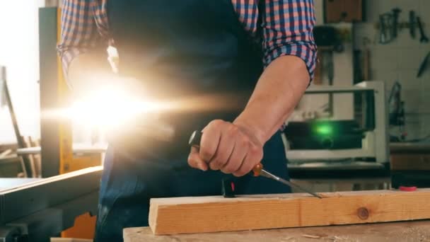 Een timmerman gebruikt een hamer en een beitel om hout te verwerken — Stockvideo