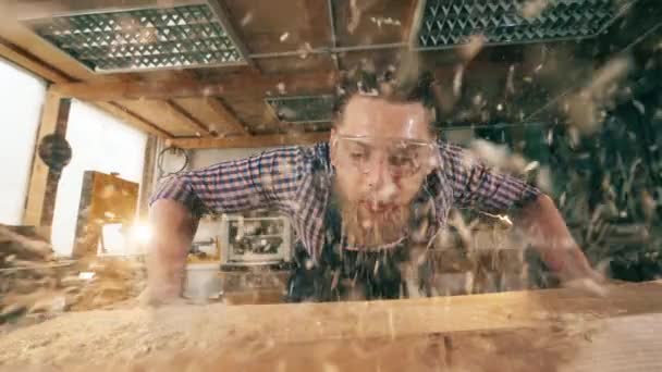 Las virutas de madera están siendo voladas por un artesano. Artesano trabajando en carpintería . — Vídeo de stock