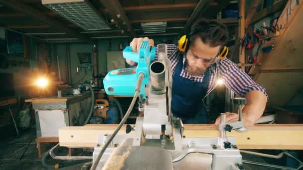 La tabla de madera está siendo cortada mecánicamente por un trabajador masculino. Artesano trabajando en carpintería . — Vídeos de Stock