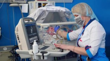 Kadın pediatrist bir bebek kontrol, tarama makinesi kullanarak.