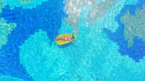 Een vrouw rust in een blauw zwembad, zwevend op een matras. — Stockvideo