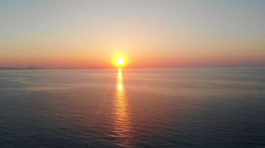 Mavi deniz üzerinde turuncu günbatımı.