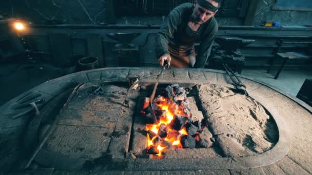 Человек проверяет огонь угля в кузнице . — стоковое видео