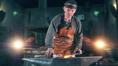 Profesyonel demirci, örs üzerinde çekiç olan bir bıçağı şekillendirir.