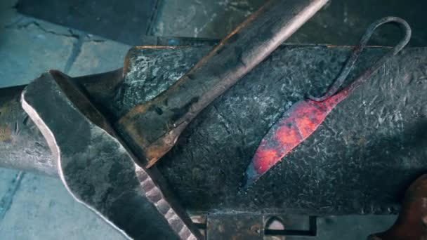 Металлические инструменты лежат на большом наковальне в кузнице . — стоковое видео