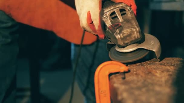 한 남자가 위조에서 일하는 동안 앵글 그라인더를 사용합니다.. — 비디오
