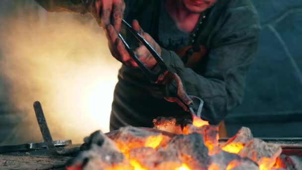 Professional blacksmith holds tongs while heating a knife. — Stock Video