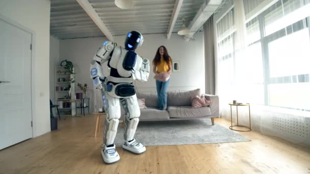 Chica feliz y un robot bailan juntos en una habitación. Robot, cyborg y concepto humano . — Vídeo de stock