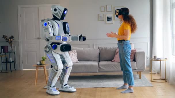 Droid kadın hareketlerini kopyalar, o da VR gözlükleri takarken. Cyborg ve insan konsepti. — Stok video