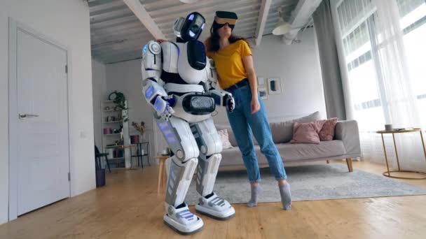 En flicka i VR-glasögon kramar en vit Cyborg. — Stockvideo