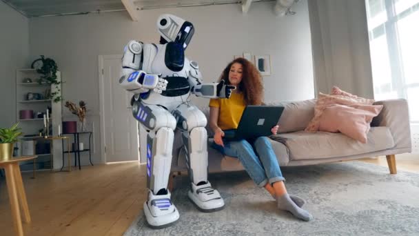 로봇, 사이보그 및 인간의 개념. 한 소녀와 사이보그가 방에서 노트북을 가지고 일합니다.. — 비디오