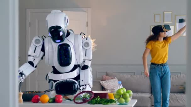 Un robot cucina il pasto mentre una ragazza indossa occhiali VR . — Video Stock