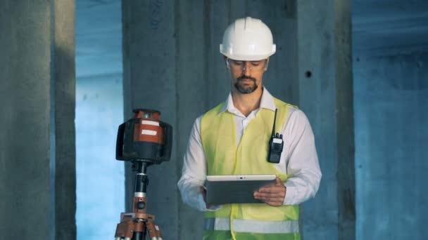 Constructor, tipos de ingeniero en una tableta que trabaja en un sitio de construcción . — Vídeo de stock