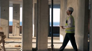 Erkek mühendis, inşaat işçisi bir tabletle yürür. Steadicam vurdu.