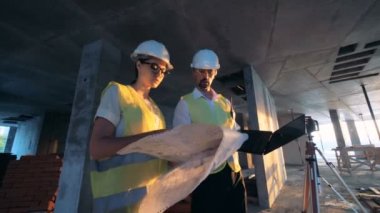 İşçiler, mimarlar bir bina planını kontrol ediyor, yakın yukarı.