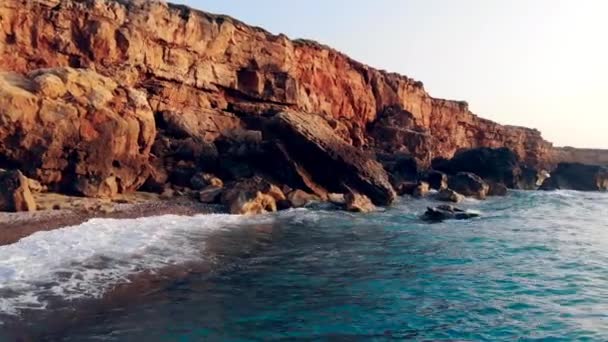 Mavi deniz gün batımı arka planda kayalıkların karşı atıyor. Havadan görünüm. — Stok video